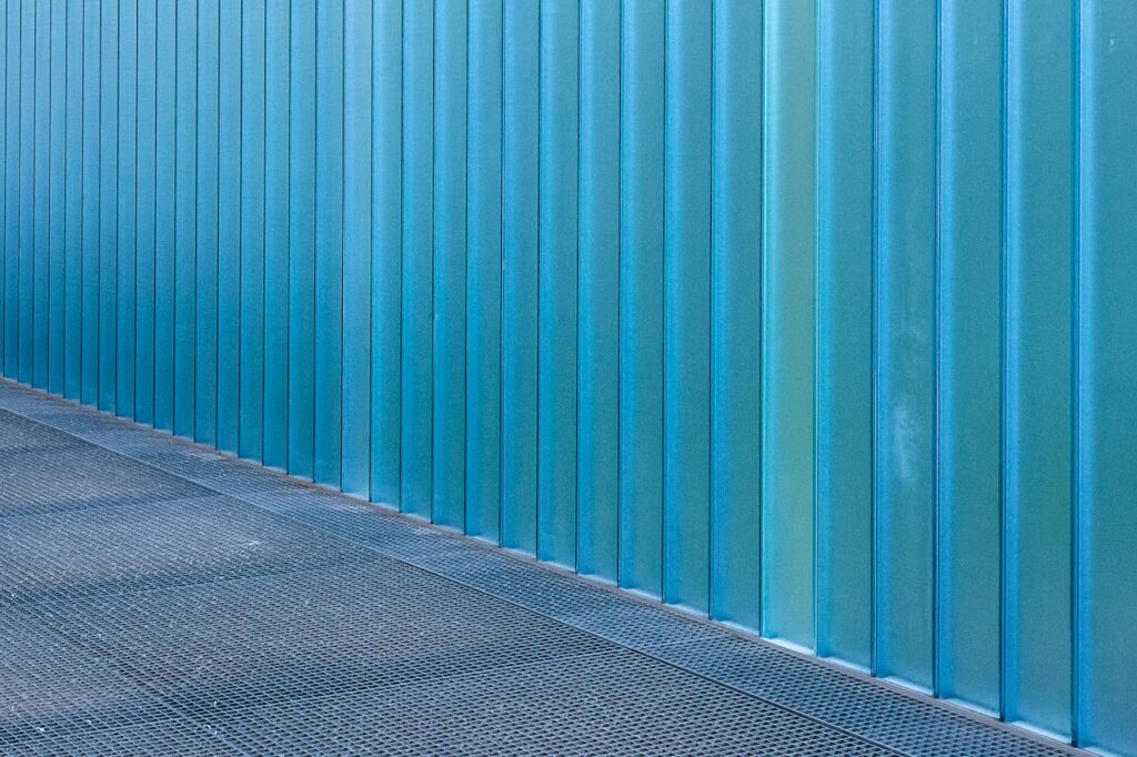 Blue corrugated metal wall with a textured floor, showcasing modern industrial design.